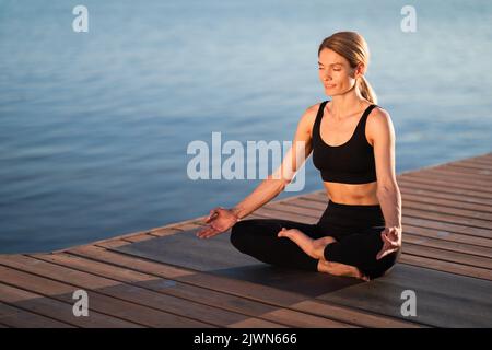 Wellbeing Concept. Beautiful Middle Aged Female In Activewear Meditating Outdoors Stock Photo