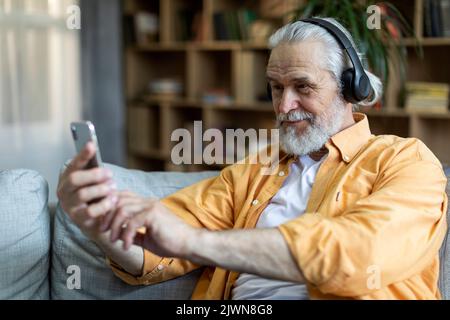Positive grandfather using wireless headset and cell phone Stock Photo