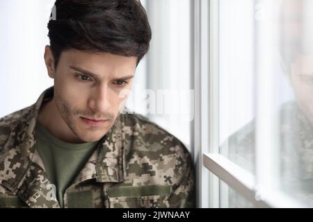 depressed military guy standing next to window, closeup Stock Photo
