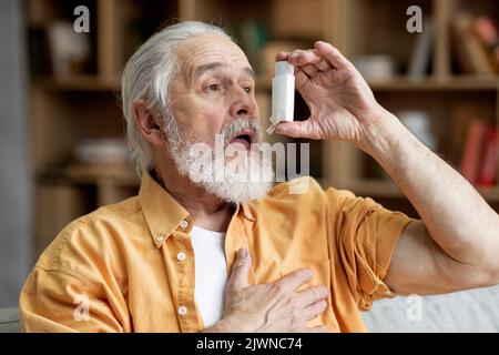 Senior man using asthma inhaler for allergies Stock Photo