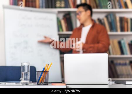 Asian Teacher Having Class Via Video Call On Laptop Indoor Stock Photo