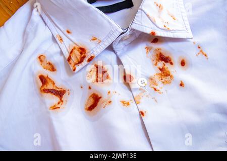 Food stains on shirt. Top view tomato sauce dirt on white shirt. Stock Photo