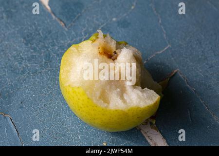 A worm eats a fruit on an authentic blue cracked background. Stock Photo