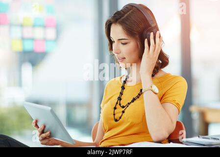 Catching up on some vids. a young businesswoman watching something on her tablet while sitting in the office. Stock Photo