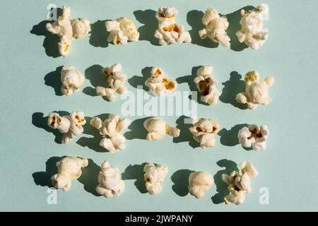 Rowes of salt popcorn on the light blue background. Stock Photo