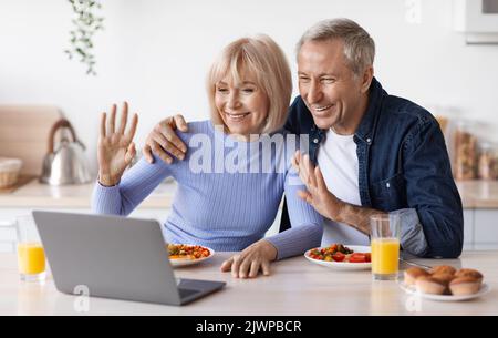 Happy senior couple making video call while having breakfast Stock Photo