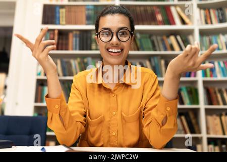Online tutoring concept. Cheerful young woman in glasses having video conference with students Stock Photo