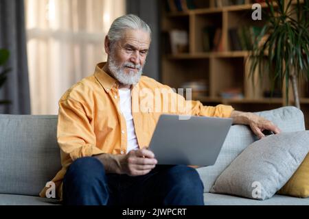 Happy senior man using modern laptop at home Stock Photo