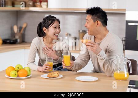 positive japanese spouses having fun while eating at kitchen Stock Photo