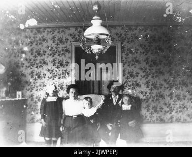 Family group collected under kerosene lamp. Familjegrupp samlad under fotogenlampa. Stock Photo
