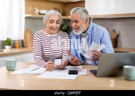 Smiling Elderly Spouses Checking Receipts While Planning Family Budget At Home Stock Photo