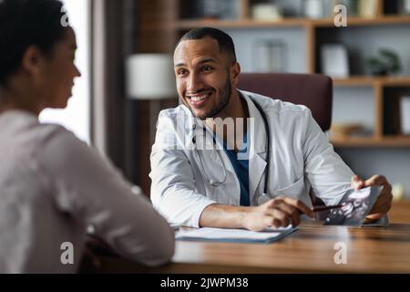 Smiling middle eastern doctor showing female patient ultrasound image Stock Photo