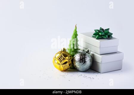 Christmas composition of a gray gift box with a green bow, gold and silver Christmas balls and a green Christmas tree candle on a gray background with Stock Photo