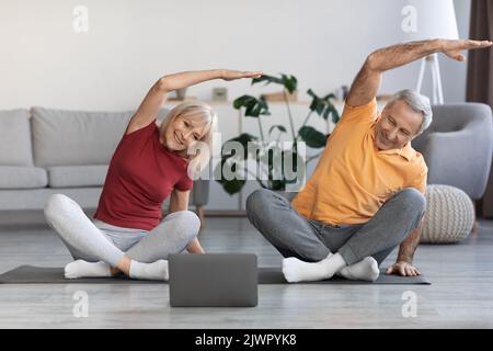 Sporty senior spouses training at home, using computer Stock Photo