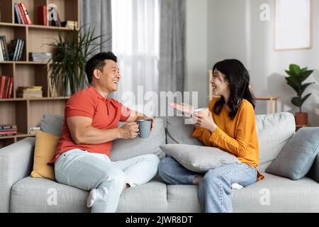 Relaxed chinese lovers enjoying conversation, drinking coffee Stock Photo