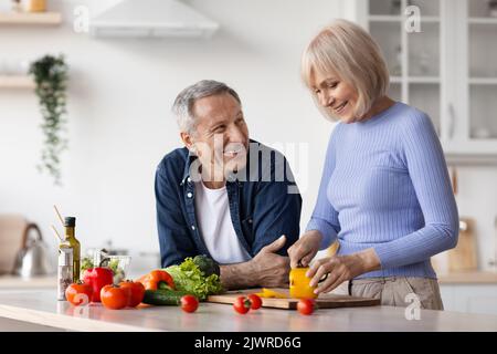 Attractive senior woman cooking and talking to husband Stock Photo