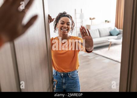 Cheerful African American Woman Waving Hand Meeting Somebody At Home Stock Photo