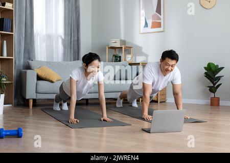 Motivated asian man and woman training at home, using computer Stock Photo