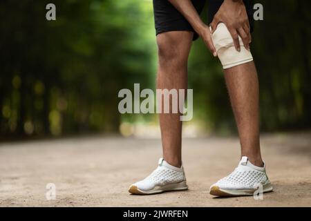 Unrecognizable sportsman wrapping injured knee with elastic bandage Stock Photo