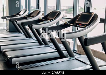 Sport Equipment. Modern Treadmills With Control Panels Standing In Row At Gym Stock Photo