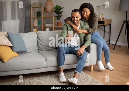 African American Husband And Wife Using Phone Sitting At Home Stock Photo