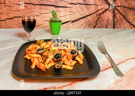 Pasta salad with tomato, black olives and anchovies. Stock Photo