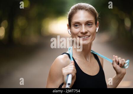 Athletic young woman doing workout outdoors, using skipping rope Stock Photo