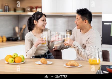 Happy asian spouses having fun while eating at kitchen Stock Photo
