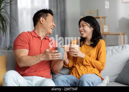 Positive korean lovers drinking tea, having conversation Stock Photo