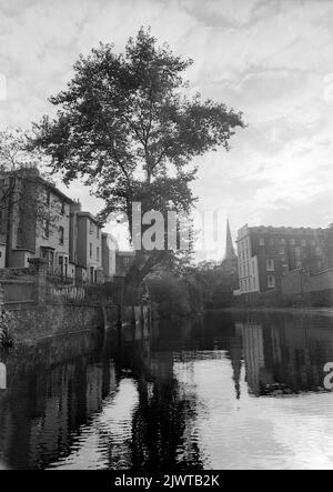 London, England, circa 1967. A view from the Regent’s Canal near Camden, London. Ahead is Regent’s Park Road bridge. On the right is a building situated in St Mark’s Square and on the left are the backs of houses in St. Mark’s Crescent. In the distance is the spire of St. Mark’s Church. Stock Photo