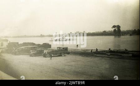 Normandy, France, September 1928. Ferry No.4 (1925-1934) crossing the River Seine at Caudebec-en-Caux. Cars and Charabanc buses are parked in the foreground. Children are playing on the foreshore. Stock Photo