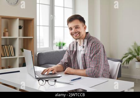 Successful young businessman working on laptop with electronic documents sitting in office. Stock Photo