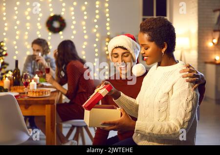 Man surprises his beloved woman by giving her present during family Christmas dinner. Stock Photo