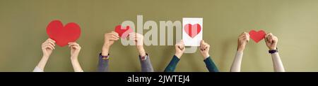 Banner with group of people holding red heart greeting cards against green background Stock Photo