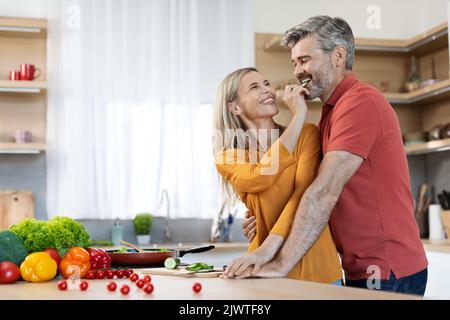 Happy middle aged spouses preparing delicious dinner together Stock Photo