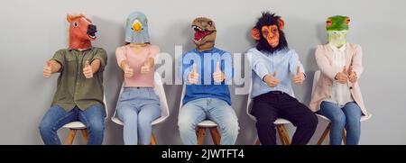 Group of happy strange men and women wearing funny animal masks showing thumbs up Stock Photo