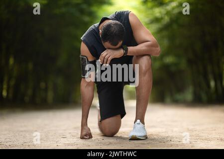 Black sportsman feeling bad while jogging by park Stock Photo