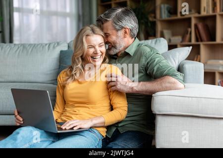 Happy Moments. Romantic Middle Aged Spouses Using Laptop And Bonding At Home Stock Photo