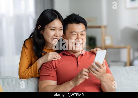 Cheerful chinese lovers having video chat with friends, copy space Stock Photo