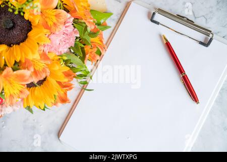 Happy Teachers Day, boss day concept card and bouquet.Bouquet of beautiful fresh flowers with clipboard and pen on white background. Floral mock up Stock Photo