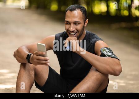 Positive black athlete having snack, resting after workout outdoors Stock Photo