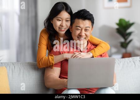 Happy korean couple using computer together at home Stock Photo