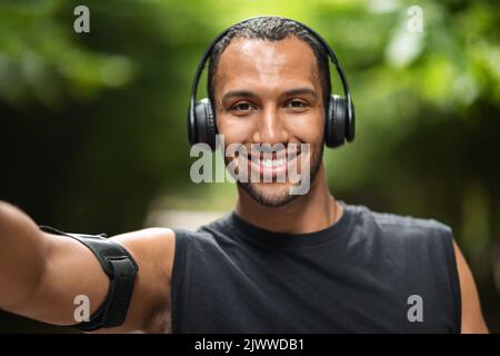 Happy black guy taking selfie while exercising at park Stock Photo