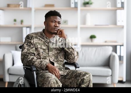 Depressed black man sitting in wheelchair, looking at copy space Stock Photo