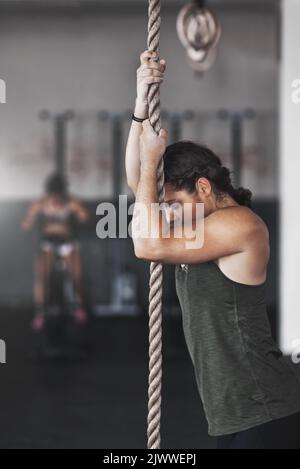 Readying herself for the climb. a young woman climbing a rope at the gym. Stock Photo