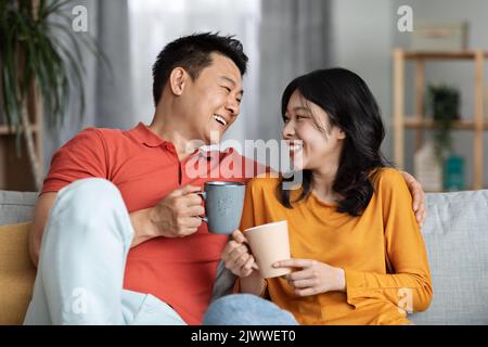 Portrait of positive asian lovers drinking tea, having conversation Stock Photo