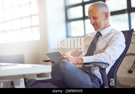 Installing the latest must have apps for a modern businessman. a mature businessman using a digital tablet in an office. Stock Photo
