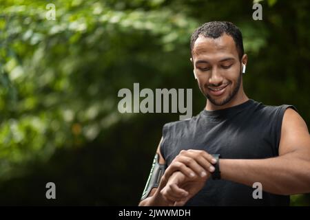 Handsome young black sportsman set his fitness tracker Stock Photo