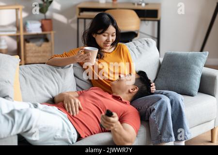 Positive japanese man and woman spending weekend together at home Stock Photo