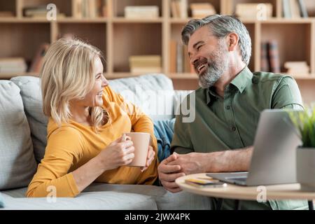 Portrait Of Happy Middle Aged Spouses Chatting And Drinking Coffee At Home Stock Photo